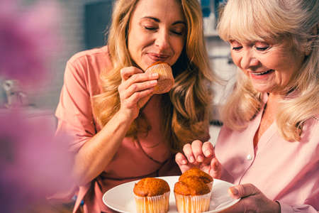 Beautiful senior woman and daughter baking in the kitchen - Grandmother preparing desserts at home with family, concepts about cooking and healthy eatingの写真素材