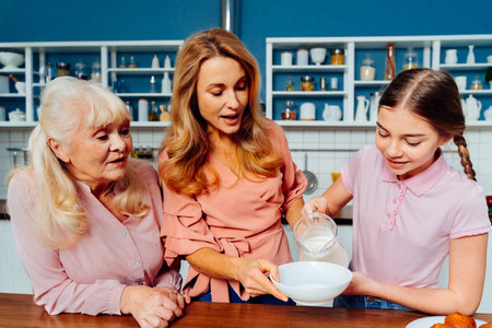 Beautiful senior woman and family baking in the kitchen - Grandmother preparing desserts at home with daughter and nephew, concepts about cooking and healthy eatingの写真素材