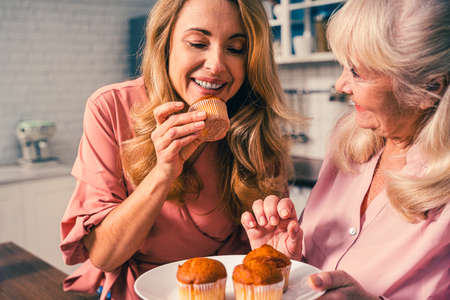 Beautiful senior woman and daughter baking in the kitchen - Grandmother preparing desserts at home with family, concepts about cooking and healthy eatingの写真素材