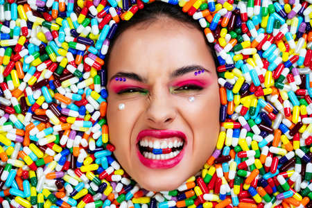 Artistic image of a beautiful woman sunk inside colored pills and capsules.の写真素材