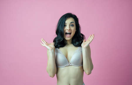 Image of a beautiful woman posing in lingerie on a pink colored backgroundの写真素材