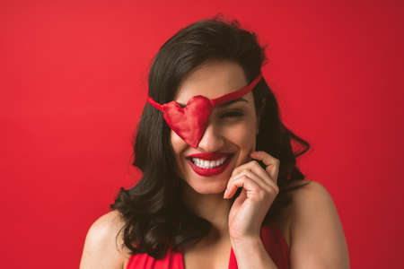 Beautiful woman dressing in red with heart shaped eye patchの写真素材
