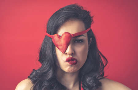 Beautiful woman dressing in red with heart shaped eye patchの写真素材