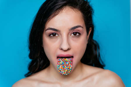 Artistic image of a female mouth with colored sprinkles on her tongueの写真素材