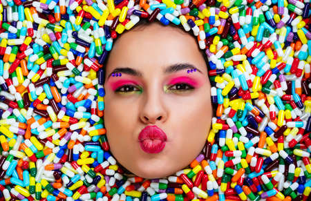 Artistic image of a beautiful woman sunk inside colored pills and capsules.の写真素材