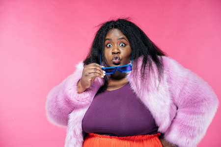 Image of a beautiful woman posing in a furry coat on a pink backgroundの写真素材