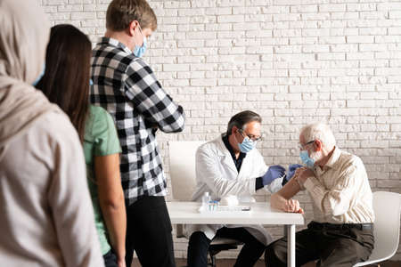 Covid-19 (coronavirus) vaccination campaign in a clinic - People getting vaccinated from doctor and nurse to prevent corona virus outbreak in a vaccination pointの写真素材