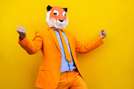 Cool man wearing 3d origami mask with stylish colored clothes - Creative concept for advertising, animal head mask doing funny things on colorful backgroundの写真素材
