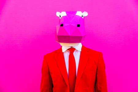 Cool man wearing 3d origami mask with stylish colored clothes - Creative concept for advertising, animal head mask doing funny things on colorful backgroundの写真素材
