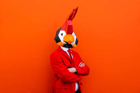 Cool man wearing 3d origami mask with stylish colored clothes - Creative concept for advertising, animal head mask doing funny things on colorful backgroundの写真素材