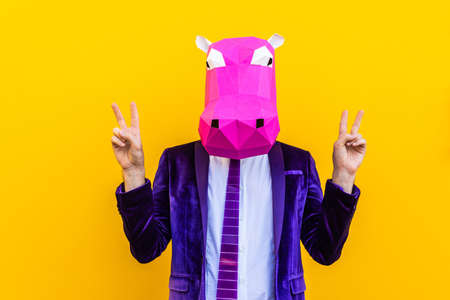 Cool man wearing 3d origami mask with stylish colored clothes - Creative concept for advertising, animal head mask doing funny things on colorful backgroundの写真素材