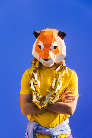 Cool man wearing 3d origami mask with stylish colored clothes - Creative concept for advertising, animal head mask doing funny things on colorful backgroundの写真素材