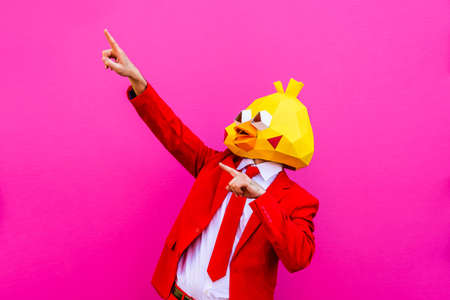 Cool man wearing 3d origami mask with stylish colored clothes - Creative concept for advertising, animal head mask doing funny things on colorful backgroundの写真素材
