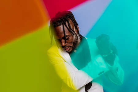 Artistic portrait with gel lights. Handsome man posing on colored backgrounds