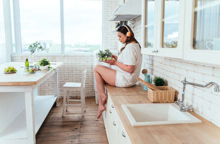 Lifestyle moments of a young woman at home. Woman preparing a salad in the kitchenの写真素材