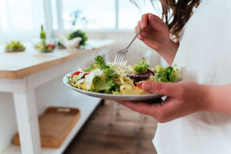 Lifestyle moments of a young woman at home. Woman preparing a salad in the kitchenの写真素材