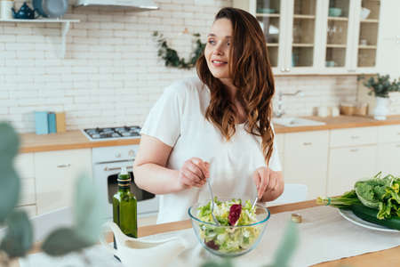 Lifestyle moments of a young woman at home. Woman preparing a salad in the kitchenの写真素材