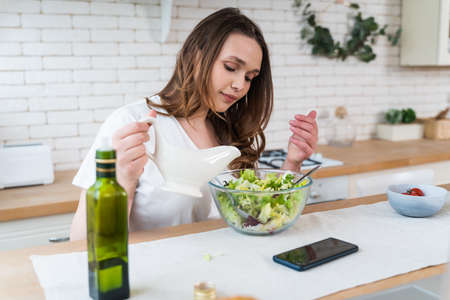 Lifestyle moments of a young woman at home. Woman preparing a salad in the kitchenの写真素材