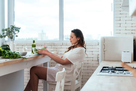 Lifestyle moments of a young woman at home. Woman preparing a salad in the kitchenの写真素材