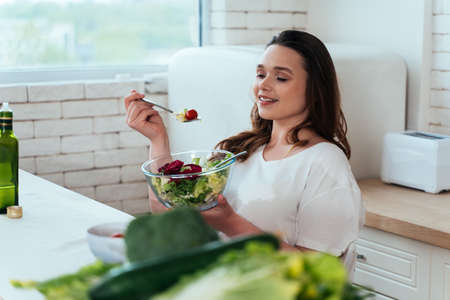 Lifestyle moments of a young woman at home. Woman preparing a salad in the kitchenの写真素材