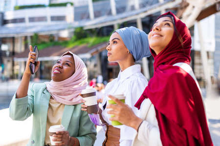 Multiethnic group of muslim girls wearing casual clothes and traditional hijab bonding and having fun outdoors - 3 arabic young girlsの写真素材