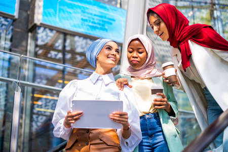 Multiethnic group of muslim girls wearing casual clothes and traditional hijab bonding and having fun outdoors - 3 arabic young girlsの写真素材