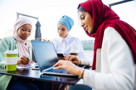 Multiethnic group of muslim girls wearing casual clothes and traditional hijab bonding and having fun outdoors - 3 arabic young girlsの写真素材