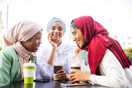 Multiethnic group of muslim girls wearing casual clothes and traditional hijab bonding and having fun outdoors - 3 arabic young girlsの写真素材