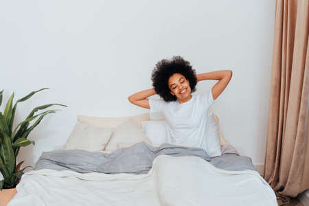 Afro-american girl resting in bed at home - Beautiful woman relaxing at homeの写真素材