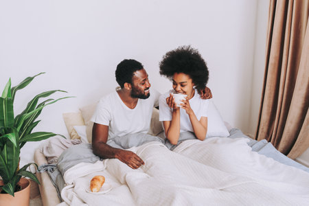 Afro american couple in bed - Real beautiful and cheerful pair of lovers at homeの写真素材