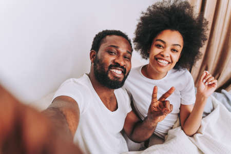 Afro american couple in bed - Real beautiful and cheerful pair of lovers at homeの写真素材