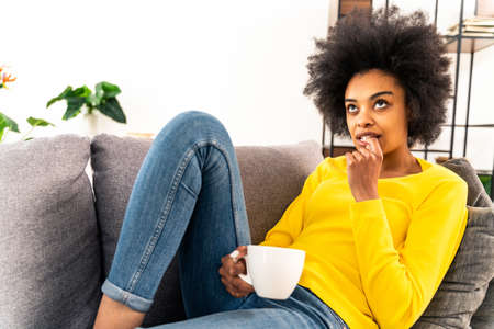 Afro-american girl drinking mug of coffee and relaxing at home