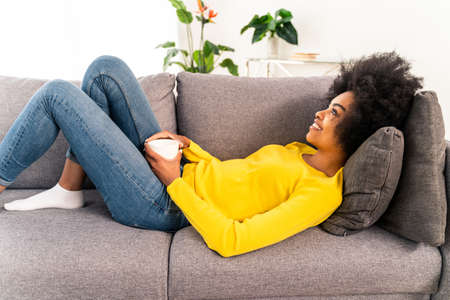 Afro-american girl drinking mug of coffee and relaxing at home