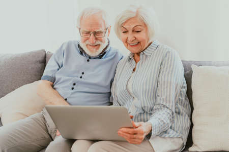 Elderly couple shopping online on internet with computer laptop at home - Beautiful happy senior...