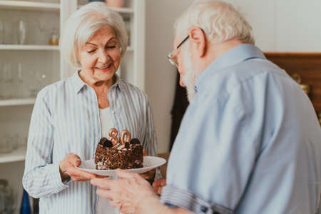 Beautiful senior couple celebrating anniversary with birthday cake - Elderly couple having birthday...