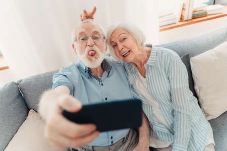 Happy senior couple having fun and taking photograph on mobile phone to share online on social networks - Elderly people using modern technology, grandparents taking selfieの写真素材