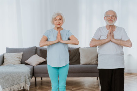 Sportive senior couple doing fitness and relaxation exercises at home - Elderly people training to stay healthy and fitの写真素材