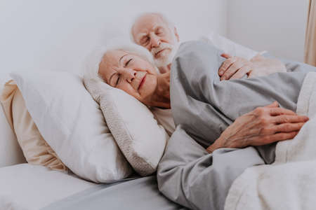Beautiful senior couple enjoying time together at home - Elderly people sleeping in bed at homeの写真素材