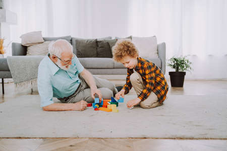 Grandparents and grandson playing at home - Family at home, grandfather taking care of nephewの写真素材