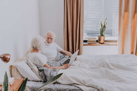 Beautiful senior couple enjoying time together at home - Moder elderly couple surfing the internet on laptop computerの写真素材