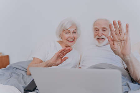 Beautiful senior couple enjoying time together at home - Moder elderly couple surfing the internet on laptop computerの写真素材