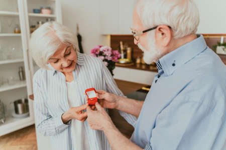 Senior couple wedding proposal, - Elderly man asking his woman to marry him, engagement ring giftの写真素材