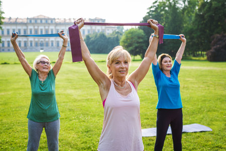 Multiethnic group of senior women training at park with fitness instructor - Active elderly people doing sport in the natureの写真素材
