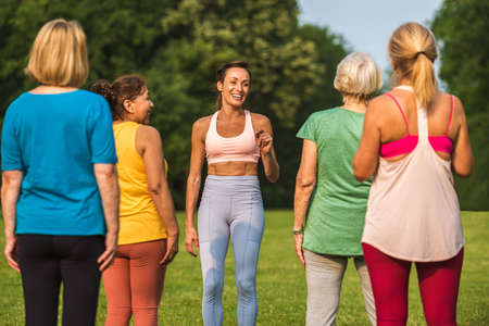 Multiethnic group of senior women training at park with fitness instructor - Active elderly people doing sport in the natureの写真素材