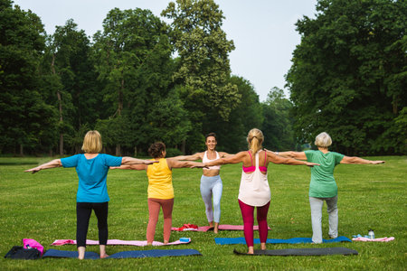 Multiethnic group of senior women training at park with fitness instructor - Active elderly people doing sport in the natureの写真素材