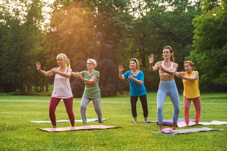 Multiethnic group of senior women training at park with fitness instructor - Active elderly people doing sport in the natureの写真素材