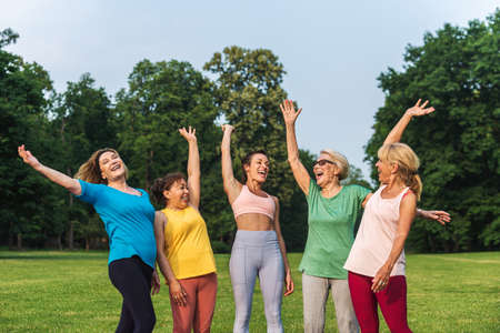 Multiethnic group of senior women training at park with fitness instructor - Active elderly people...
