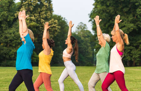Multiethnic group of senior women training at park with fitness instructor - Active elderly people...