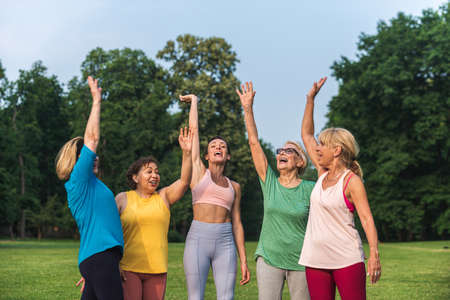 Multiethnic group of senior women training at park with fitness instructor - Active elderly people...