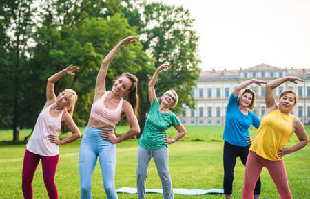 Multiethnic group of senior women training at park with fitness instructor - Active elderly people doing sport in the natureの写真素材